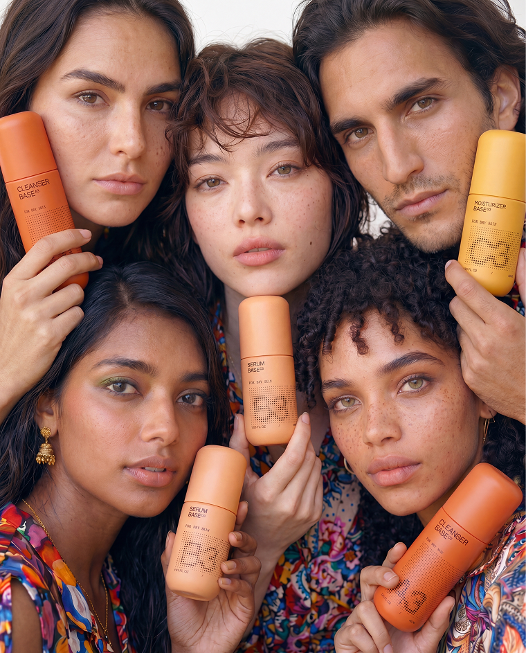 Diverse group of people holding Cleanser Base, Serum Base, and Moisturizer Base bottles.